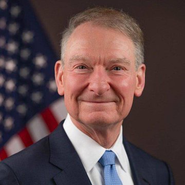 The image shows a professionally taken portrait of a smiling older man in a dark suit and blue tie, with an American flag visible in the background. The accompanying post identifies him as SEC Chair Paul Atkins, who announced the agency would move forward on crypto regulation regardless of congressional action on the CLARITY Act.