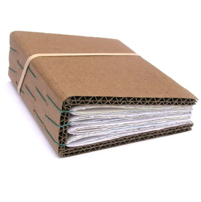 A handmade journal with a corrugated cardboard cover, green thread stitching along the spine, and a cream-colored elastic band holding it closed, filled with white pages.