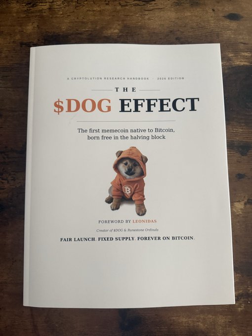 A book cover titled 'THE $DOG EFFECT - A CRYPTOVOLUTION RESEARCH HANDBOOK 2026 EDITION' featuring a Shiba Inu dog wearing an orange Bitcoin hoodie.