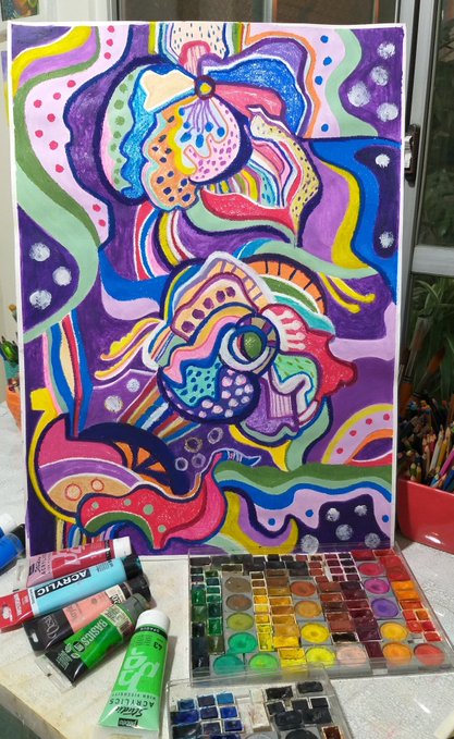 A vibrant, colorful abstract painting featuring stylized fish and swirling patterns in purple, pink, blue, yellow, and green, displayed alongside tubes of acrylic paint and a watercolor palette.
