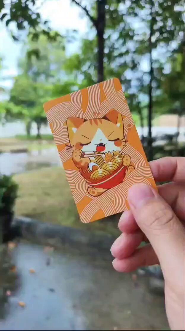 The image features a hand holding up an orange card with a cat design, including a bowl of noodles as part of its face. The text "Great work @Tangem #self Custody #security" is also present in the image. This suggests that someone has created this card and posted it on social media to showcase their creativity or share something interesting about cats.