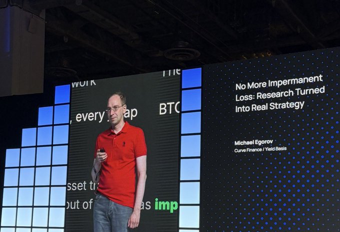 A man in a red polo shirt giving a presentation on stage. The screen behind him displays the title "No More Impermanent Loss: Research Turned Into Real Strategy" by Michael Egorov, Curve Finance / Yield Basis.