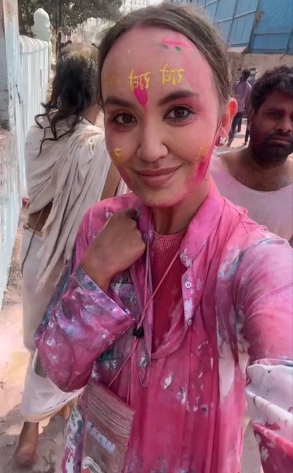 A smiling woman with her face and clothing covered in vibrant pink Holi powder takes a selfie, with "this" written in yellow on her forehead, capturing a colorful cultural moment.

The image shows her celebrating Holi, adding a personal, human touch to her tech-focused bio as a 45-year-old crypto content creator from Russia based in Georgia.