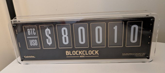 A Coinkite Blockclock Mini device displaying the live BTC/USD price as $80,010 in clear white flip-style digits.