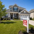 A small, low-resolution image of a two-story suburban home with a green lawn and a 'For Sale' sign in the front yard.