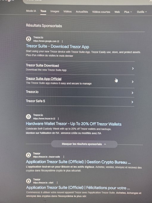 Screenshot of a Google search page showing sponsored results at the top for "Trezor" — including ads like "Trezor Suite – Download Trezor App" and a "Hardware Wallet Trezor – Up To 20% Off" offer — highlighting how phishing ads can appear above legitimate results before users even click anything.