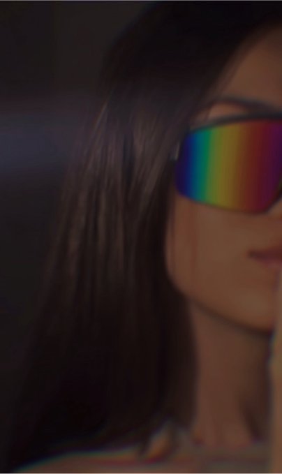 A close-up dark-toned image of a person with long dark hair wearing rainbow-reflective sunglasses, with only part of their face visible.