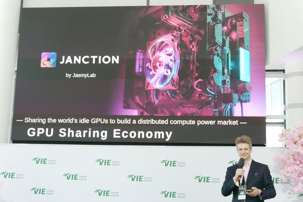 The image features a man standing next to a large screen, possibly at an event or conference. He appears to be presenting something related to the topic of "sharing the world's idle GPGs (GPGPU) with distributed computing power market". The background includes a banner that reads "JANCTION by JASMY Lab", indicating that this is likely a joint research project between the lab and other institutions.