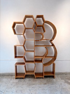 A wooden shelving unit featuring a honeycomb hexagonal design with curved backing, placed on a tiled floor against a white wall.