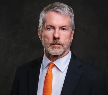 A distinguished-looking man with gray hair and a beard, wearing a dark suit, light blue shirt, and orange tie, gazes thoughtfully at the camera, embodying the calm confidence and conviction described in the post celebrating Strategy's massive $1.4 billion unrealized Bitcoin gain.