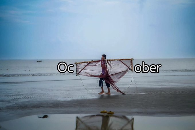 A serene beach scene showing a person walking along the shoreline carrying a fishing net, with the text 'October' overlaid across the image.