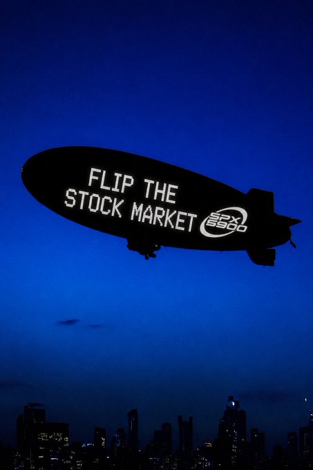 A blimp silhouetted against a dark blue sky displaying the message 'FLIP THE STOCK MARKET' alongside the 'S&P 6900' logo.