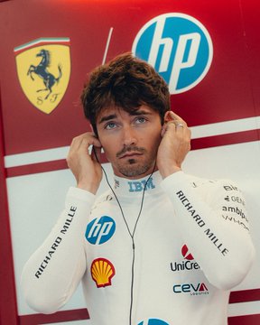 Charles Leclerc of Scuderia Ferrari puts on his earpiece in full concentration mode, dressed in his white HP and Richard Mille-sponsored race suit with the iconic Ferrari prancing horse emblem visible behind him.