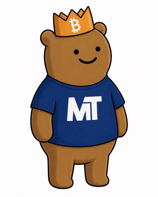 The image features a brown teddy bear wearing a blue shirt with the letters "MT" printed on it, standing upright against a white background. The teddy bear has a crown on its head, giving it an air of regality or importance. The caption reads "$GRIZZY", which is likely a reference to the teddy bear's plush appearance and the fact that it is wearing a crown.