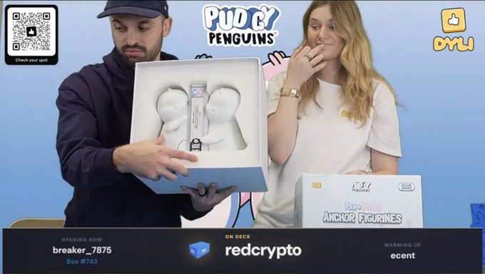 Two presenters on a livestream for 'Pudgy Penguins' holding a box containing Pudgy Penguin figurines, with on-screen text showing 'OPENING NOW breaker_7875', 'ON DECK redcrypto', and 'WARMING UP ecent'.