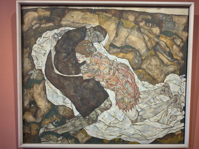 A framed painting depicting two intertwined figures in an expressionist style with muted earth tones and white drapery.