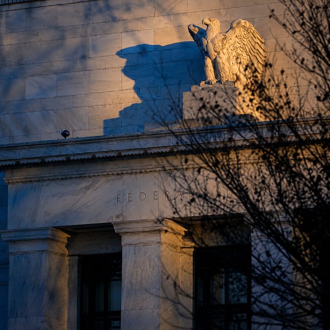 An eagle statue perches atop a marble building inscribed "FEDERAL," its golden facade bathed in sunset light—evoking the looming Federal Reserve decision highlighted by shifting rate hike odds and soaring oil prices.