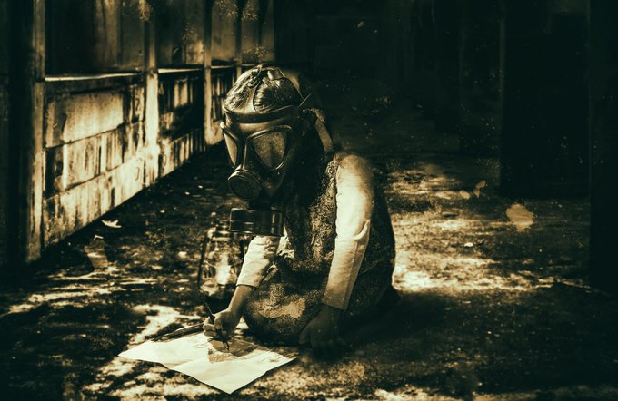 A sepia-toned, dystopian-style photograph of a small child wearing a gas mask, sitting on the ground drawing in an abandoned building.