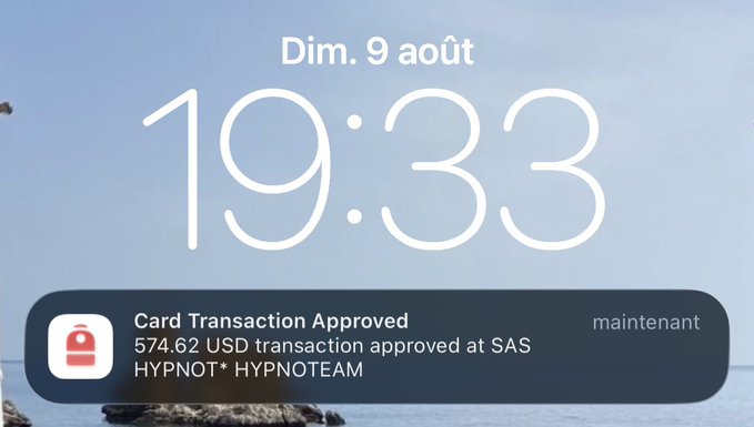 An iPhone lock screen displays the time '19:33' on Sunday, August 9 ('Dim. 9 août'), with a notification showing 'Card Transaction Approved' for a 574.62 USD transaction at 'SAS HYPNOT* HYPNOTEAM'.