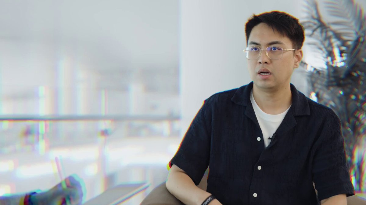 The image shows a man wearing glasses sitting down and looking off into the distance, possibly lost in thought or daydreaming. The background features a blurred view of a building, suggesting an urban setting. The caption for this image reads "focus on what is in the image and how it relates to the post."