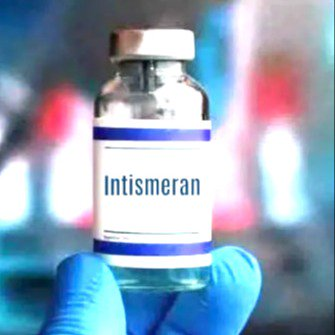 A gloved hand holds up a glass vial labeled 'Intismeran' with a blue stripe, set against a blurred background.