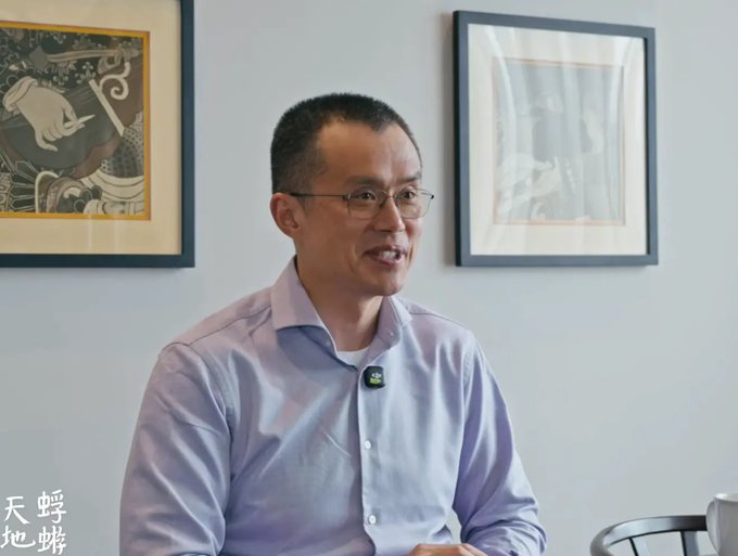 A photograph of an Asian man wearing glasses and a light blue shirt, smiling in what appears to be an interview setting with framed art behind him.