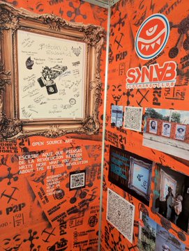An orange-themed corner display celebrating 'SNVB SECURITY BBQ', featuring a framed sketch, photos of men, and a red smiley face logo.