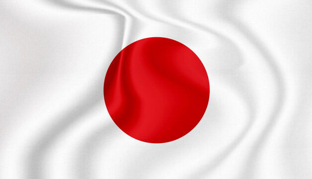 The image shows the waving flag of Japan, featuring its iconic red circle centered on a white background. It visually represents the country mentioned in the news about Nomura's Laser Digital Japan becoming Japan's first new crypto trading provider in nearly four years.