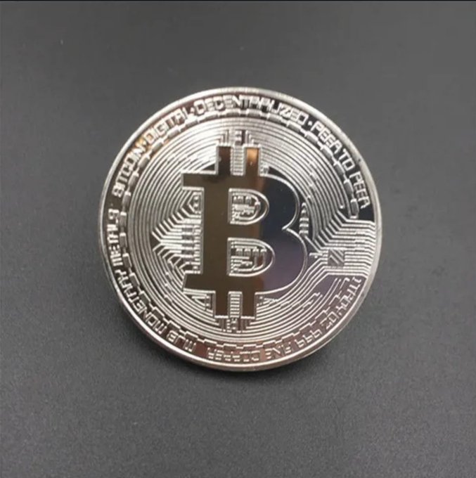 A close-up of a physical Bitcoin commemorative coin with the text 'BITCOIN DIGITAL DECENTRALIZED PEER TO PEER' engraved around the edge.