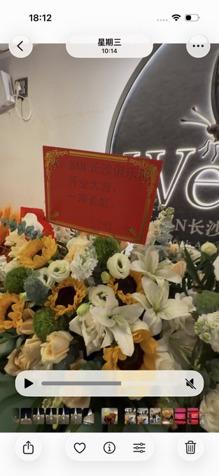 A screenshot of a photo gallery app displaying an arrangement of yellow and white flowers with a red sign reading 'PAN 长沙特派 开业大吉 一路长虹', taken on October 14 (星期三).