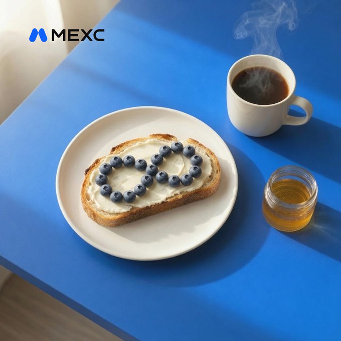 A slice of toast topped with cream cheese and blueberries sits next to a steaming cup of coffee on a bright blue table, with the "MEXC" logo and accompanying wordmark visible in the upper left. The image visually plays on the "Zero fees. Extra blueberries. GM" tagline by showcasing a generously blueberry-topped breakfast—suggesting MEXC's platform offers similarly abundant rewards, just as the toast is piled high with fruit.