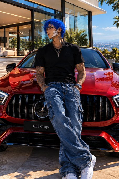 A stylized, anime-influenced depiction of a man with bright blue hair, facial bandages, and heavily tattooed arms, leaning casually against the front of a red Mercedes-Benz GLE Coupe.