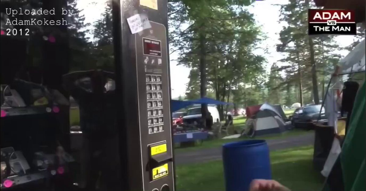 The image displays an old vending machine located next to a park. The vending machine was used for selling bitcoins at $7, with a total of 14 Bitcoins sold during that time period. A person's hand can be seen dropping change into the machine. Interestingly, there are also case studies or reports from the New Hampshire Liberty Forum in 2012 featuring the vending machine and how it collected Bitcoins to create casascius coins. These coins have a private key hidden under a tamper-proof hologram. The current value of these Bitcoins is $64,000 today, which makes them quite a valuable asset at that time.