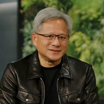 A close-up portrait of Jensen Huang, the CEO of NVIDIA, smiling and wearing a black leather jacket over a black t-shirt.