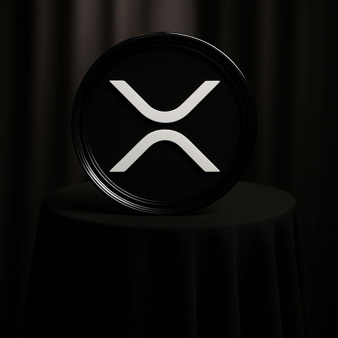 A 3D-rendered black circular token or coin displaying the white XRP (Ripple) logo, sitting on a black pedestal against a dark curtain background.
