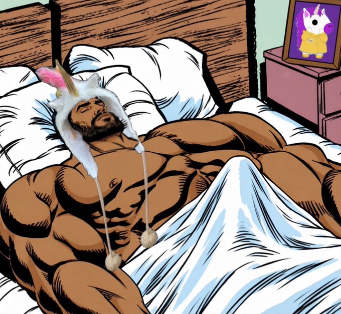 An illustrated comic-style image of a muscular bearded man sleeping in bed wearing a white bunny ear hat, with a framed picture of a cartoon unicorn in a yellow raincoat on the nightstand