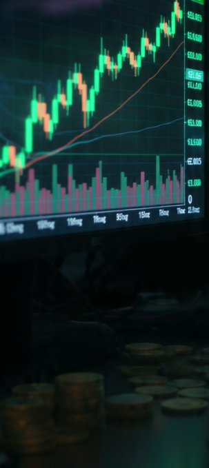 A stock market chart showing an upward trend with green and red candlesticks, displayed above stacks of coins.