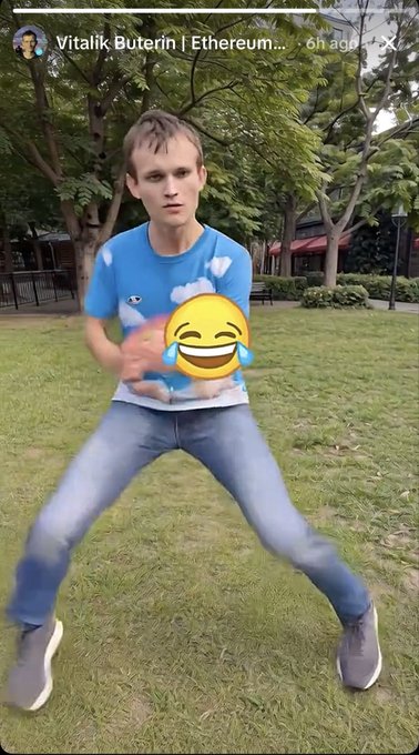 A screenshot of a social media story featuring a young man in a blue cloud-patterned t-shirt and jeans doing an exaggerated dance pose on a lawn, with a laughing-crying emoji overlay and the header "Vitalik Buterin | Ethereum..."
