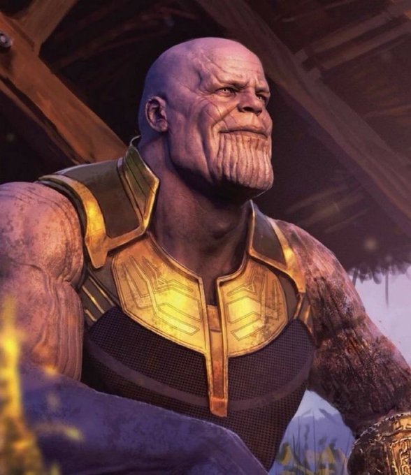 A cinematic close-up of Thanos from a superhero film, showing his purple skin, armored chest piece, and stern expression in a warm, dramatic scene.