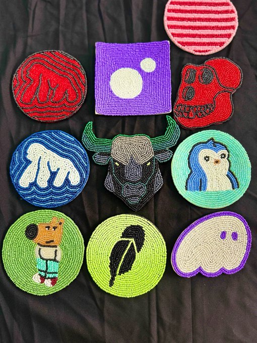 A collection of colorful beaded embroidery patches with various designs including skulls, a penguin, a character, and abstract patterns laid on black fabric.