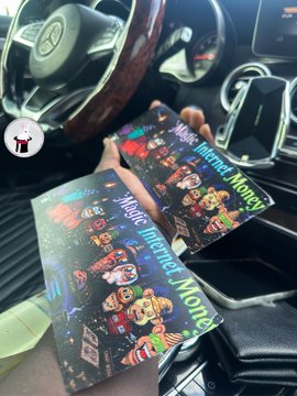 A hand holds two 'Magic Internet Money' themed cards featuring crypto logos inside a car.