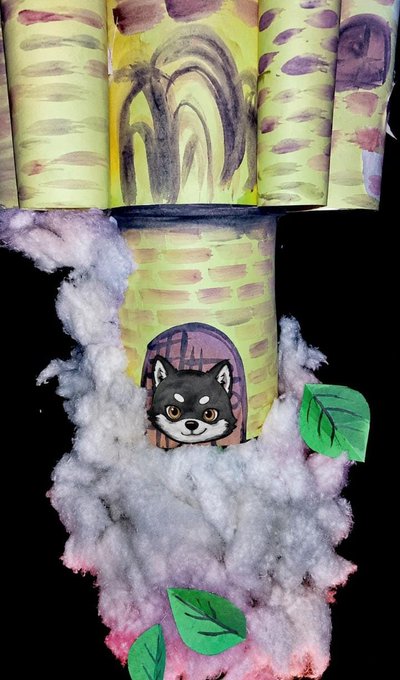 A handmade craft depicting a Shiba Inu dog's head peeking out of a paper treehouse tower surrounded by cotton cloud puffs and green leaves.