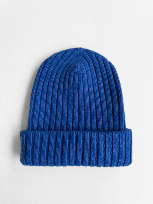 A product photo of a plain, blue ribbed knit beanie hat displayed against a solid white background.