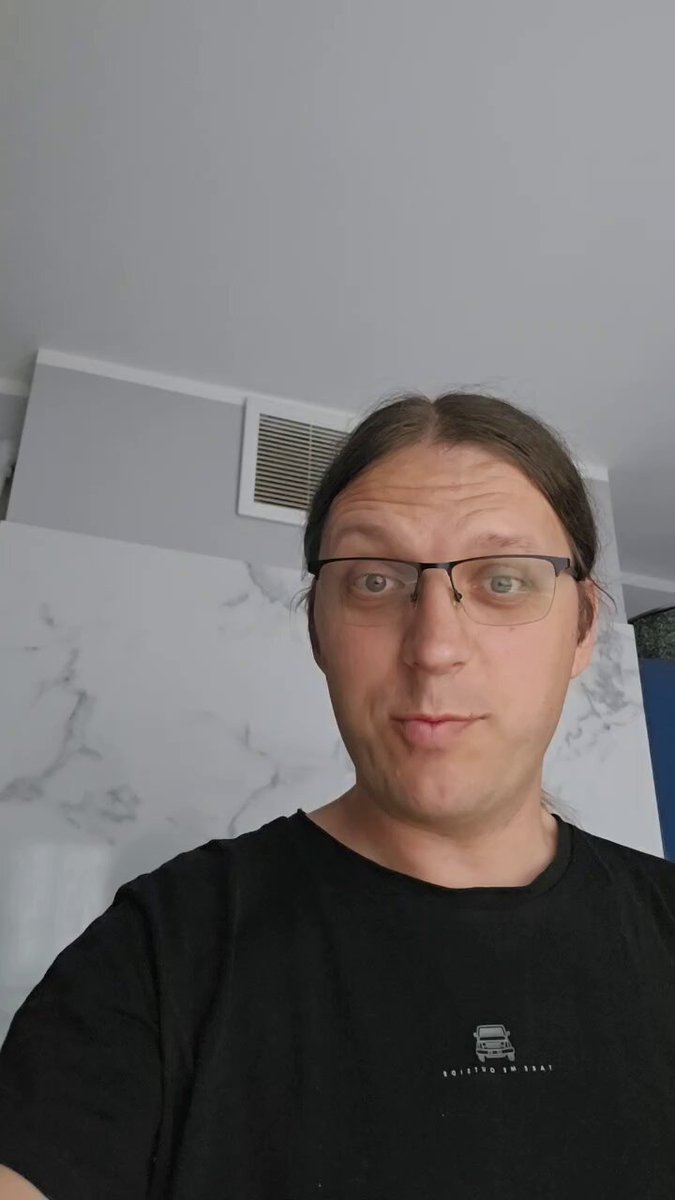 The image features a man wearing glasses, with his face turned towards the camera. He appears to be posing for a photo or selfie. The background of the image shows a white wall, which contrasts nicely with the man's black t-shirt. There is also a text overlay in the image that reads "I am not a fan of Sundays, but I do enjoy some fun and family time. $BTC will be there next week. How do you like the cauliflower that I bought my wife? Lol Let' s make some good vibes." This message seems to be related to the man's recent purchase of cauliflower for his wife as a surprise gift on Sunday, which is an example of how he enjoys spending quality time with her and making her happy.