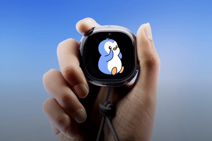 A hand holds a silver smartwatch displaying a cute penguin mascot illustration on its screen against a blue background.