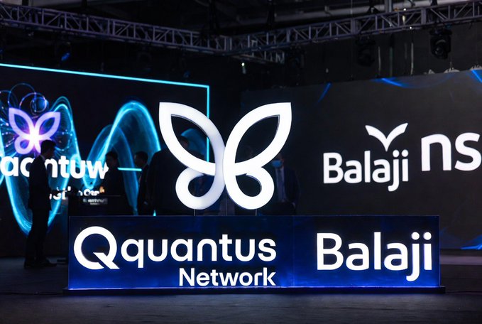 The image features a large display screen with the logos of Quantum Network and Balaji NS. The screen has a blue background with white text that reads "Only 1,000 Eigen Keys exist. Each one guarantees whitelist access to rare Quantum Echo traits." This message suggests that the company is offering exclusive access to rare Quantum Echo traits through their network. Additionally, there are two people standing in front of the display screen, possibly attending an event or discussing the content displayed on it.