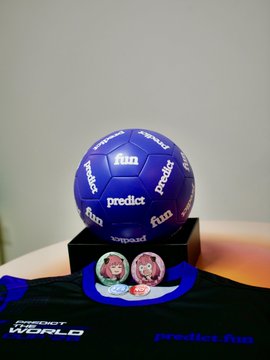A purple soccer ball branded with 'fun' and 'predict' logos sits on a black stand above a display showing two cartoon faces, with 'Energy Web World' visible below.