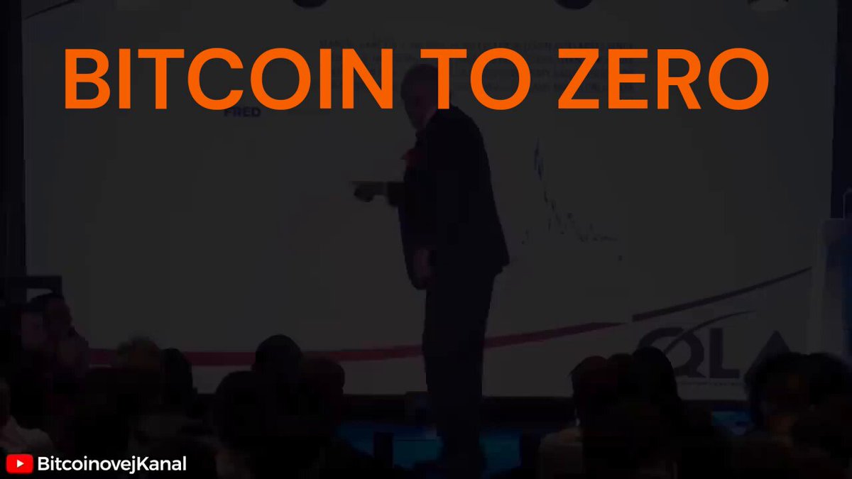 The image features a man standing on stage with a large whiteboard behind him that says "BITCOIN TO ZERO". The man appears to be giving a speech or presentation about Bitcoin, possibly discussing its current state or future implications. The audience is seated in front of the stage, attentively listening and watching the speaker.