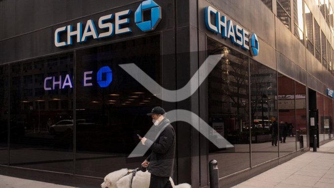 The image shows a man walking past a Chase Bank building while carrying a suitcase with two dogs at his feet. The scene also includes a car parked nearby, as well as other people walking around outside of the bank. In the background, there is a large Chase sign and an XRP logo on the side of the building.

The image also contains text that reads "BOOOOOOOOOOOOOOOOOOM!!! In a significant development for the cryptocurrency world, JPMorgan Chase has announced that it will now accept 𝐴𝑡𝑖𝑒𝑟𝑠𝑡𝑘𝑛𝑙𝑚𝑜𝑡𝑖𝑎𝑡 𝐴𝑡𝑖𝑒𝑟𝑠𝑡𝑘𝑛𝑙𝑚𝑜𝑡. Focus on what is in the image and how it relates to the post."