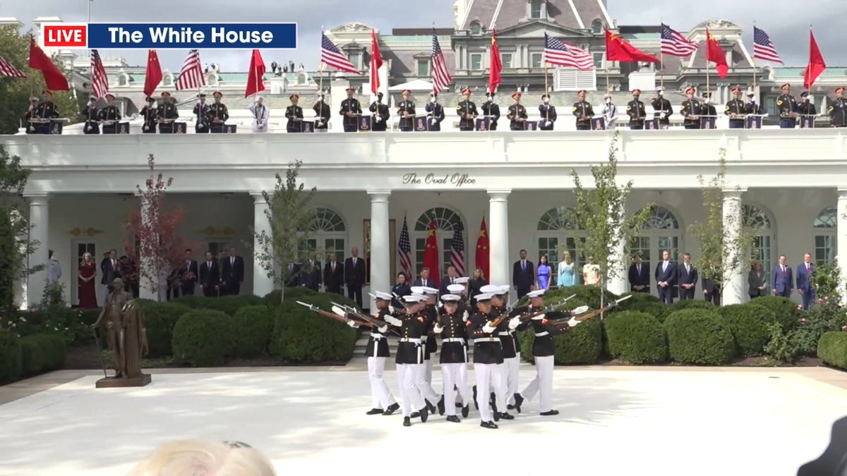 A live broadcast from "The White House" shows a ceremonial event at The Oval Office, with military honor guards marching and performing rifle drills while officials and guests look on from the colonnade.